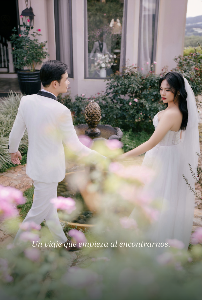 Renata y Santiago tomados de la mano entre flores en el jardín.
